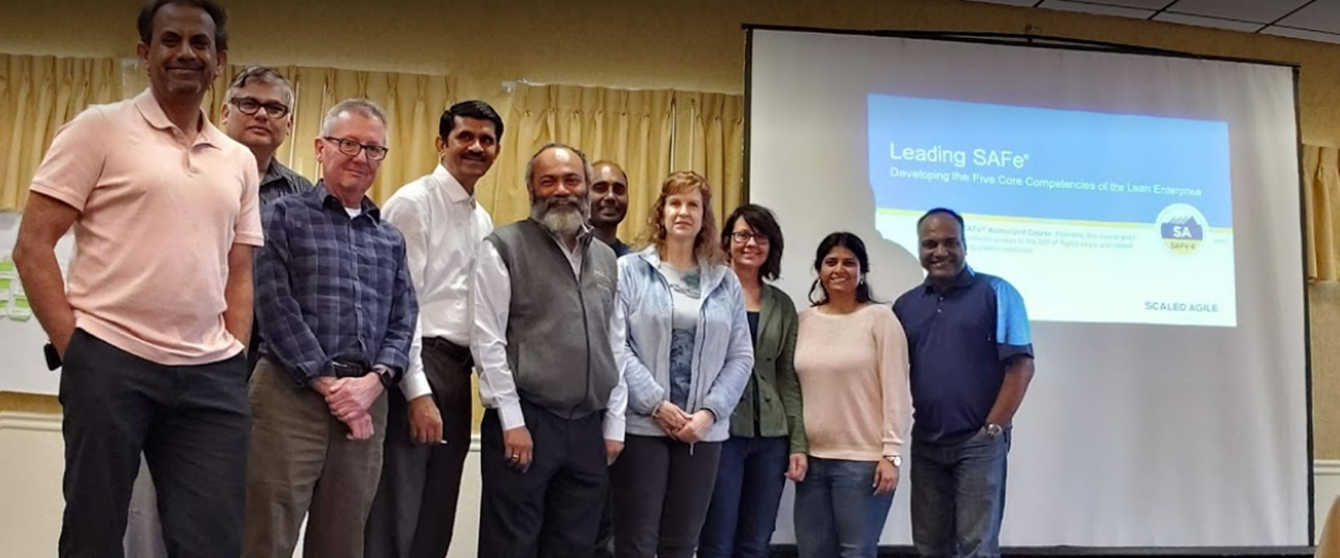Training participants gathered beside a Leading SAFe presentation